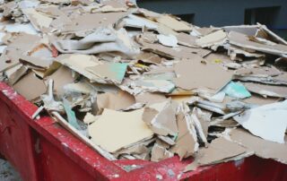 Inmage or various plasterboard off cuts of different shapes in sizes, filling a large skip.